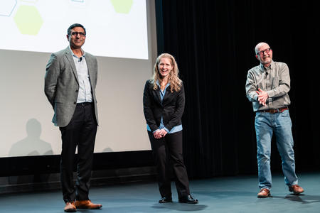 Rajaram Gopalakrishnan, Julie Olson, and Paul Jardine stand on stage and smile